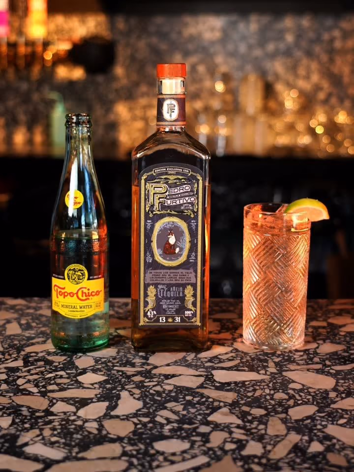 A bottle of Pedro Furtivo Añejo beside a highball on a terrazzo bar