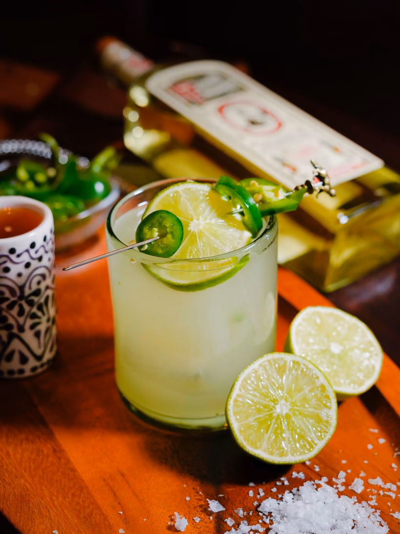 A Jalapeño Margarita with sliced jalapeños, limes and coarse salt