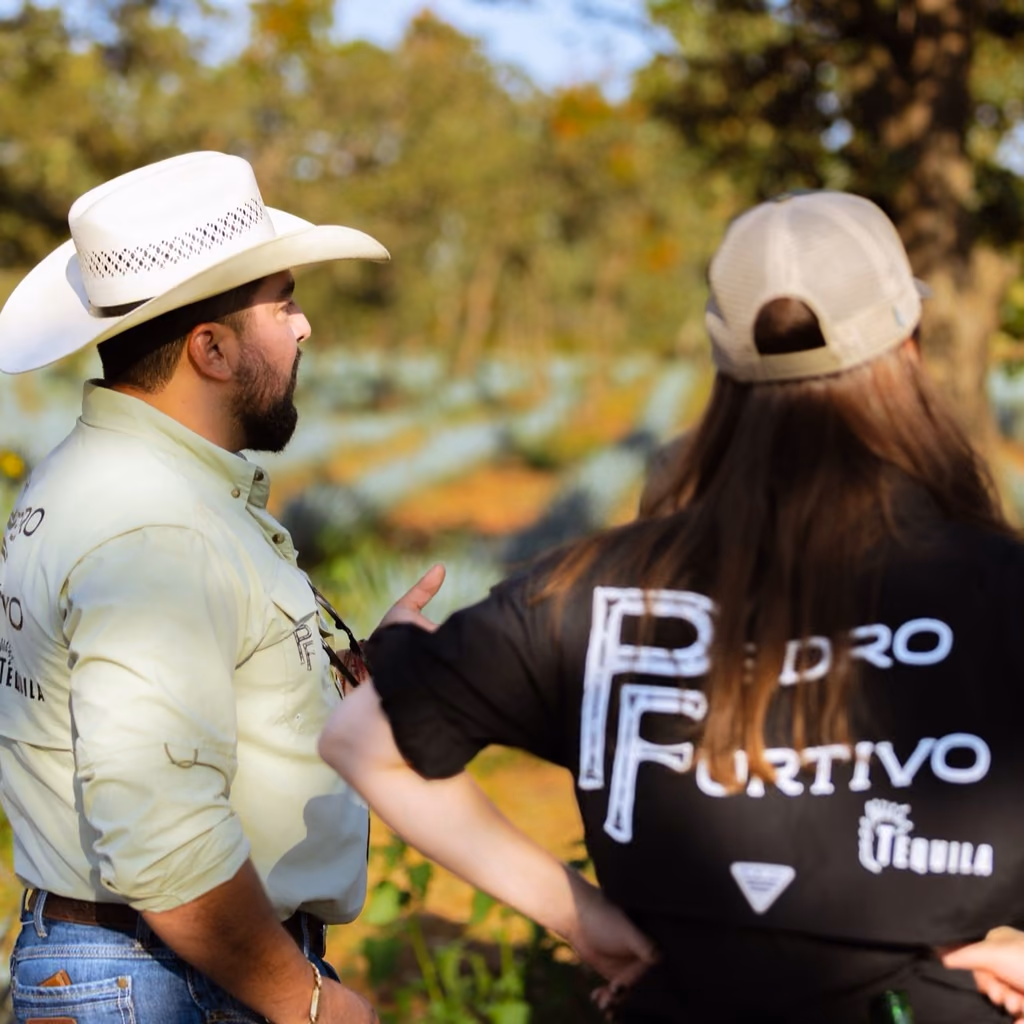 Two people talking among the blue agave rows